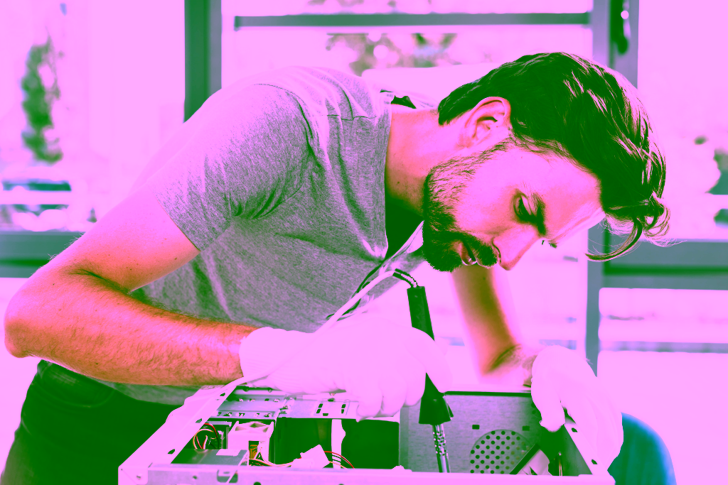 Ein Mann mit weißen Handschuhen benutzt ein Werkzeug, um Komponenten in einer Küchenmaschine zu reparieren oder zusammenzubauen.