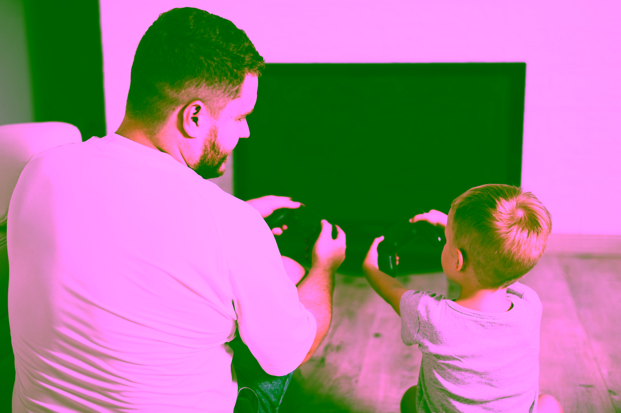 Ein Erwachsener und ein Kind sitzen auf dem Boden vor einem Fernseher, jeder hält einen Game-Controller und bereitet sich darauf vor, gemeinsam ein Videospiel zu spielen.